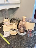 Group shot of all components: mixer base, blender jar, food processor, bowls, discs, measuring cup