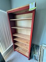 Front view showing all six shelves, red frame and natural wood interior