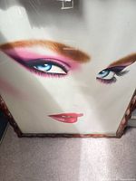 Stylized female face print in carved brown wood frame