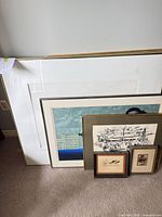 All five framed artworks leaning against wall