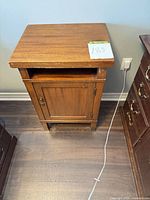 Front view showing entire nightstand with open cubby, cabinet door, brass hardware