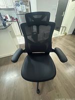 Front view of black mesh office chair showing headrest, armrests, seat, and backrest