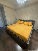 Gray IKEA Malm king bed with yellow bedding and two pillows