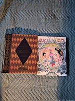 Both books side by side on quilted surface