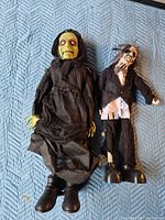 Witch and zombie props side by side on blanket.