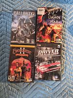 Four PC game cases laid out: Call of Duty 2, Dawn of War, EverQuest II Desert of Flames, Driver Parallel Lines