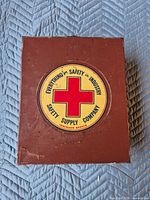 Top view of brown metal first aid box showing circular Safety Supply Company logo