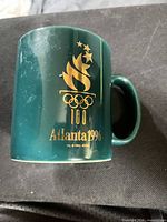 Mug front showing gold torch logo, rings, and text