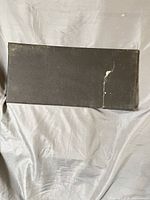 Full view of black rectangular acoustic panel with tear