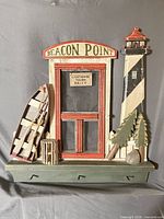 Front view showing full Beacon Point lighthouse scene and three hooks