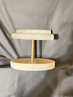 Front view of jewelry stand showing base carving, gold post, two fabric bars