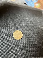 Obverse side of brass token on dark fabric background