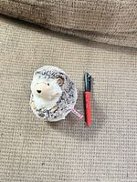 Front view of plush hedgehog beside pen for size reference