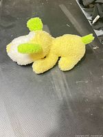 side view of yellow plush puppy showing green ear, white snout
