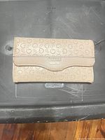 Front view showing Guess monogram print and gold logo plate