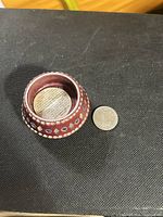 Top view showing tea light recess and exterior decoration beside coin for scale