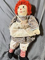 Front view of Raggedy Ann doll showing dress, pinafore, stockings, shoes, facial features