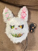 Front view of white faux-fur rabbit mask with battery pack attached
