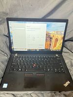 Laptop open showing screen, keyboard and Windows system information