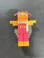 Front view of plastic Birdie figure showing pixelated design and printed arches
