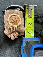 Front of suede pouch with dreamcatcher and tape measure showing height