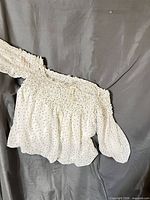 Front view of white polka dot smocked crop blouse with long sleeves