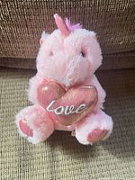 Front view of pink unicorn plush holding metallic heart embroidered "Love"