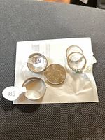 All five rings and coin for scale