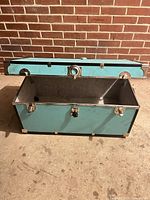 Trunk exterior open, teal panels, hardware visible