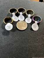 Six stainless steel band rings with size tags and quarter for scale