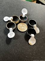 Six stainless steel rings with size 18 tabs and quarter for scale
