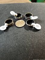 Four stainless steel rings with size tags beside a coin for scale