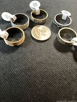 Five stainless steel rings around coin showing scale and attached size tags