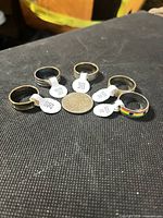 Six stainless steel rings with size 10 tags and coin for scale