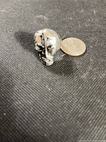 Front view of skull ring beside coin for scale