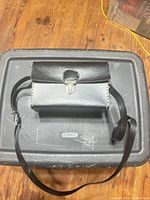 Front view of black leather camera case showing clasp and strap