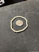 Bracelet laid flat next to U.S. quarter for scale