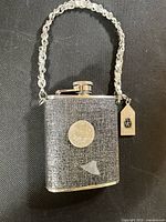 Front view showing glitter exterior, screw cap, chain handle, branded tag
