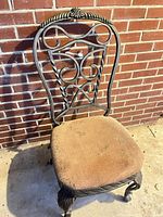 Front view of wrought iron chair against brick wall