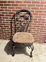 Front view of wrought iron chair showing scroll backrest, cabriole legs, and upholstered seat
