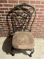 Front view of wrought iron side chair showing scroll backrest and stained seat cushion