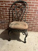 Front view of wrought iron side chair showing scrollwork back, cabriole legs, worn seat cushion