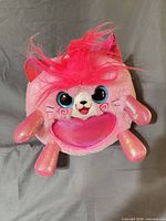 Front of pink kitty plush displaying eyes, heart pouch and limbs