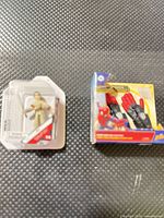 Both miniature packages side by side on textured surface