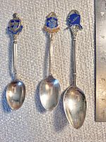 Front view of three sterling souvenir spoons beside ruler for scale