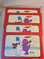 Front view of four identical Barney winter placemats stacked