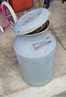 Full view of grey painted milk can with lid slightly ajar showing overall form