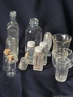 Group of assorted clear glass bottles, vials, tumblers and figurine