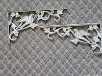 Both metal brackets showing bird motif and dimensions context