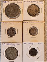 Six silver coins in cardboard holders with handwritten notes